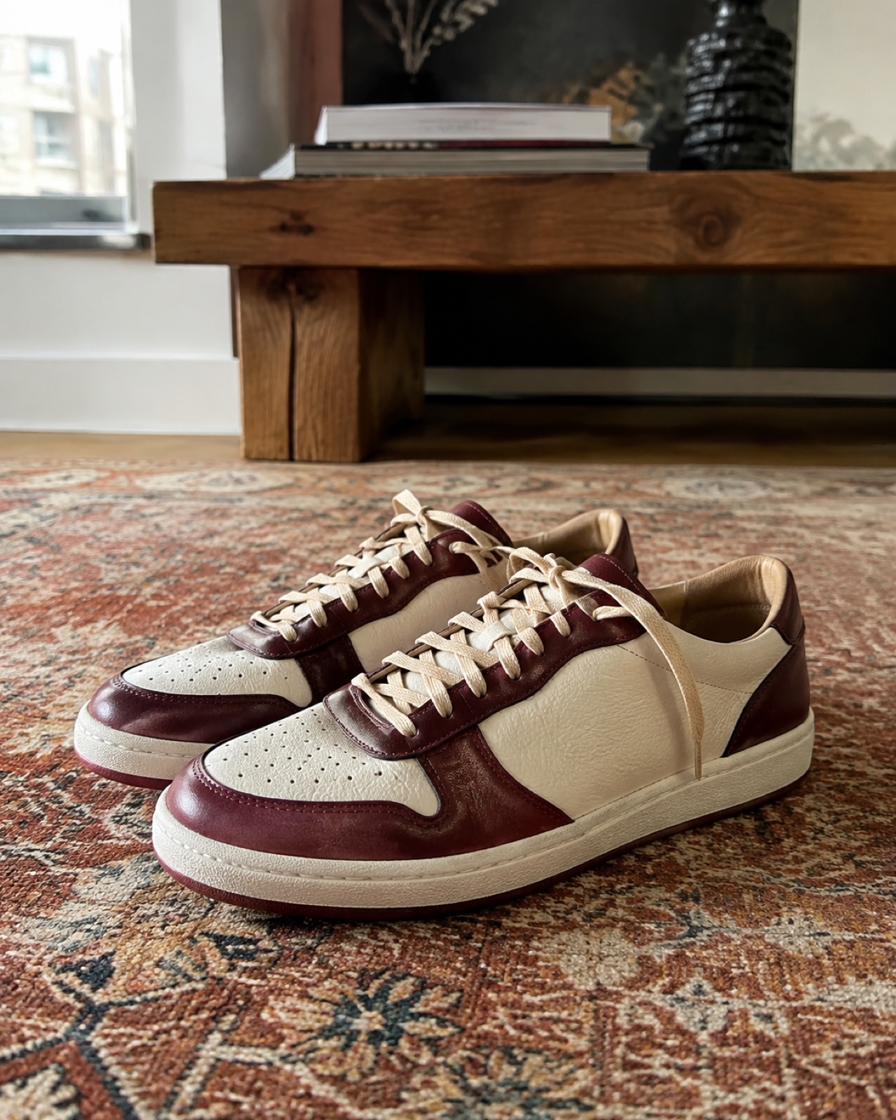 Cream and burgundy collectible sneakers on a woven rug