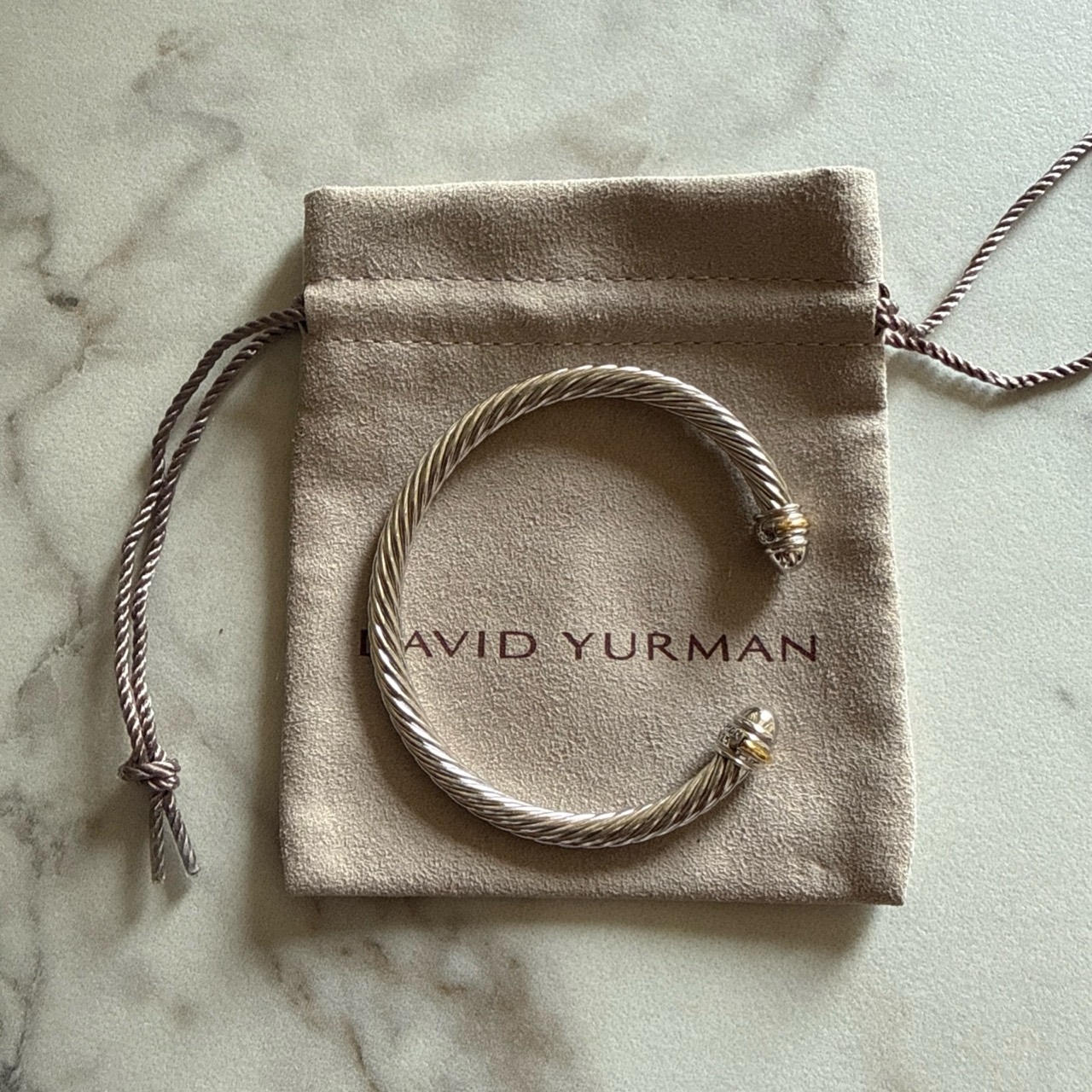 Cable cuff bracelet placed on a drawstring pouch